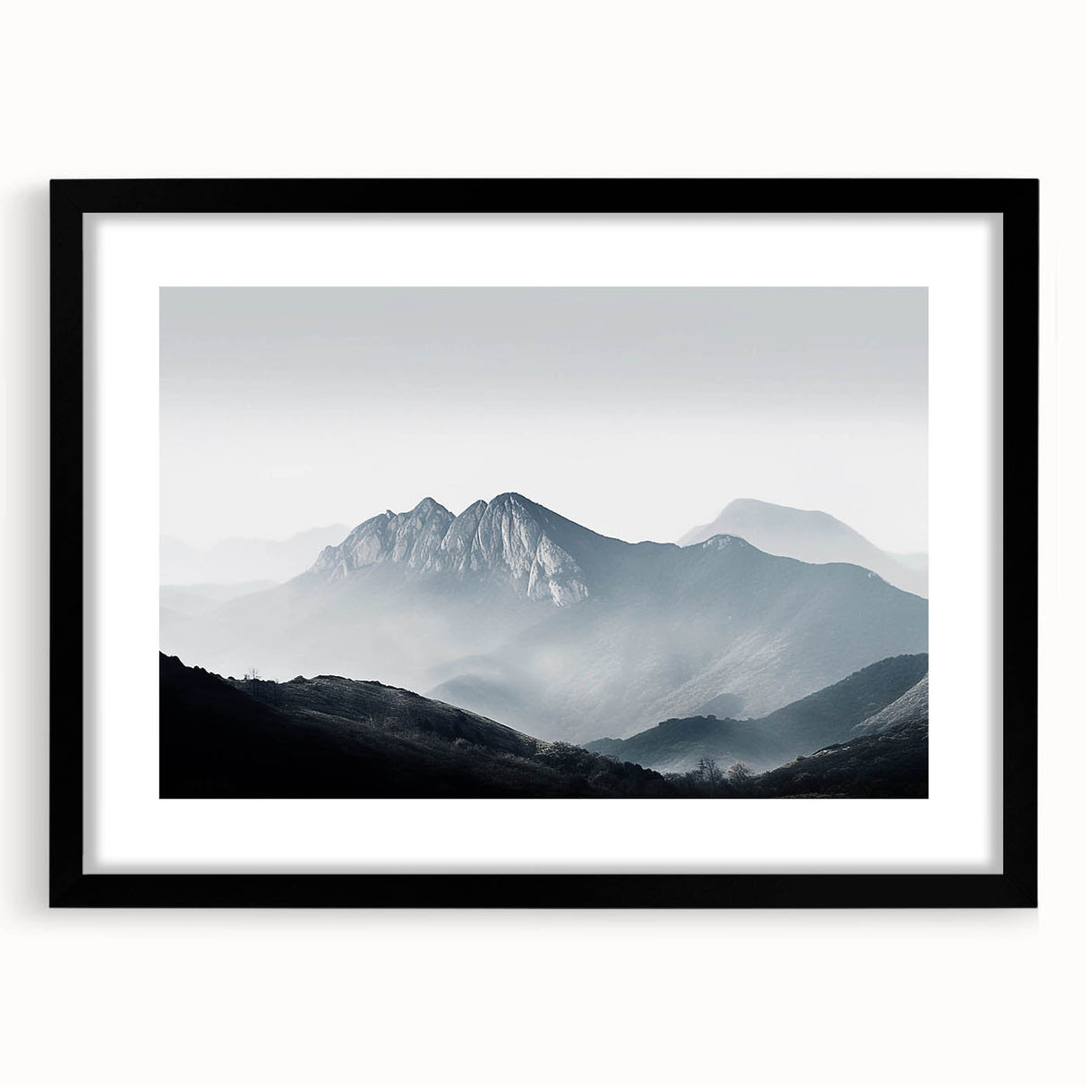 Framed wall art featuring a serene landscape design, showcasing misty mountains and soft fog, with a sleek black frame and mat, ideal for modern decor.