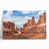 Contemporary wall art featuring a vibrant landscape design with rocky formations and warm earth tones, displayed on a stretched canvas leaning against a wall.