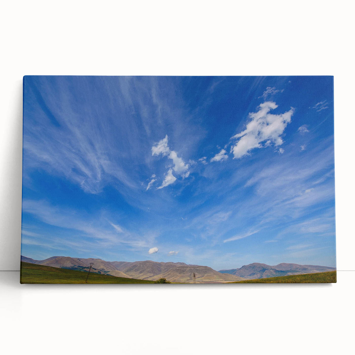Stretched canvas artwork showcasing a serene landscape with vibrant colors, featuring rolling hills and a clear blue sky, perfect for enhancing home decor.