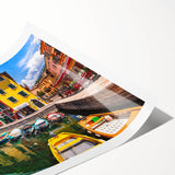 Rolled print of a vibrant landscape village scene featuring colorful houses and lush greenery, ideal for home decor or art collection, presented in a protective tube.