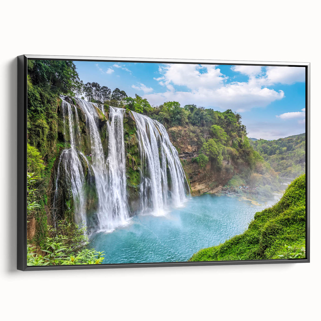 Framed landscape wall art showcasing a serene waterfall scene, featuring vibrant blues and greens, with a sleek black frame enhancing its elegance. Perfect for home decor.
