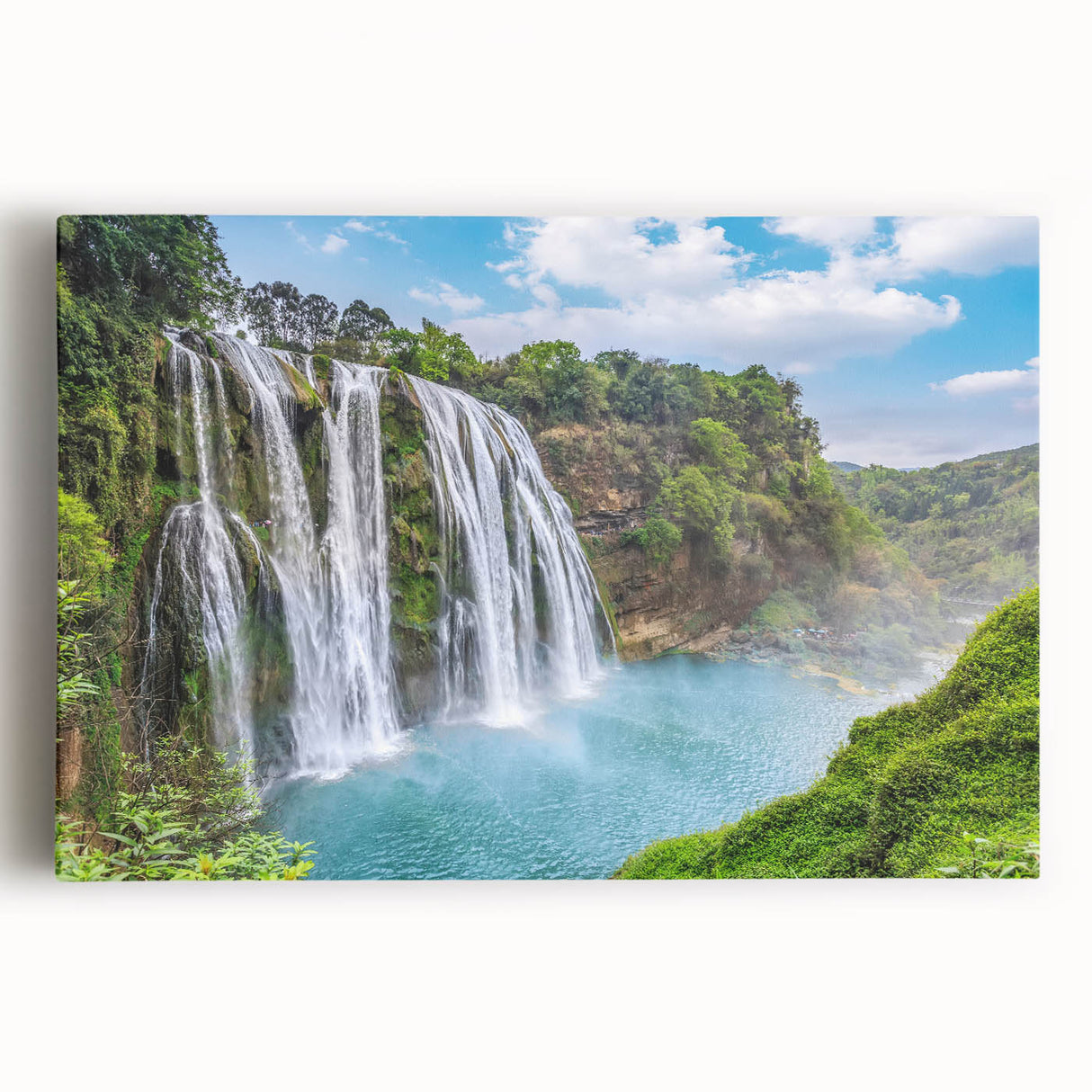 Stretched canvas artwork showcasing a vibrant landscape with a cascading waterfall surrounded by lush greenery, ideal for home decor and nature enthusiasts.