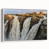 Framed canvas wall art showcasing a vibrant waterfall landscape design, featuring rich colors and detailed textures, displayed from a white side view in a modern setting.
