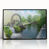 Framed acrylic wall art featuring a serene watermill landscape design with lush greenery and soft blue skies, presented in a sleek black frame for modern decor.