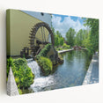 Stretched canvas wall art depicting a serene watermill landscape, showcasing vibrant greens and blues, perfect for enhancing home decor and creating a tranquil ambiance.
