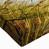 Close-up of a stretched canvas wall art featuring a vibrant landscape with windmills, showcasing a blend of greens and blues, ideal for home decor.