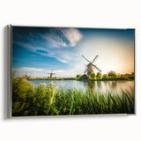Framed canvas artwork depicting a serene landscape with windmills under a vibrant sunset, featuring silver accents and a sleek side profile for modern decor. Perfect for enhancing home aesthetics.