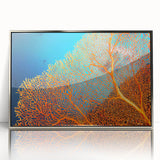 Framed wall art featuring a vibrant coral reef design with marine life, showcasing shades of blue and orange. The acrylic front enhances the colors, perfect for ocean-themed decor.