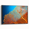Framed canvas wall art showcasing a vibrant marine life coral design, featuring intricate details in shades of blue and orange, set against a sleek black frame. Perfect for ocean-themed decor.