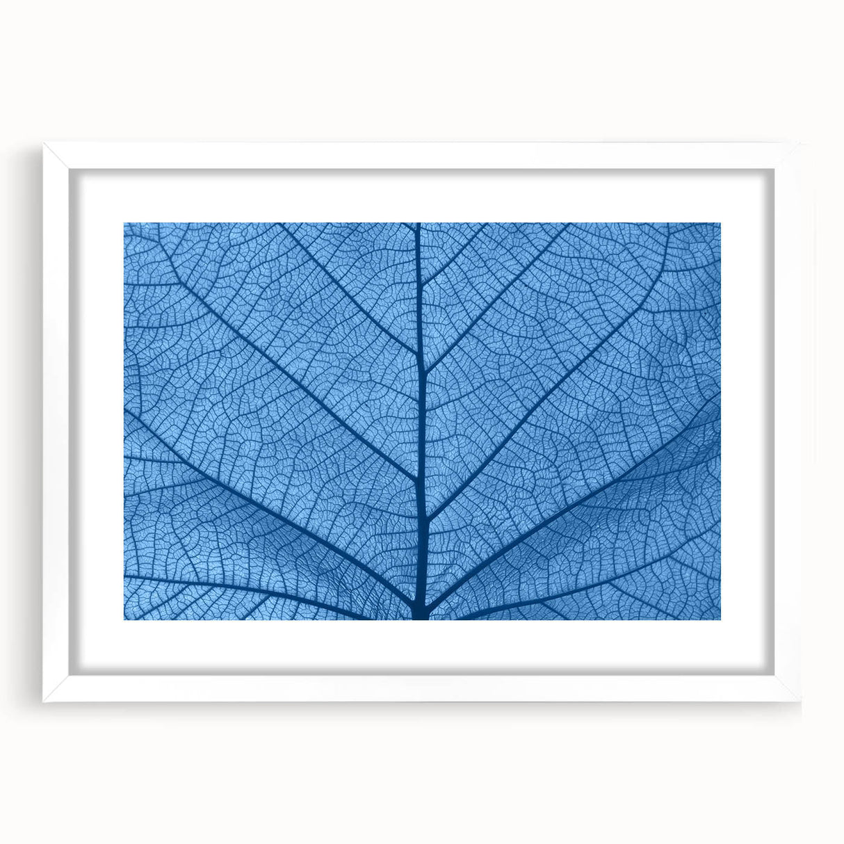Abstract art print of close-up leaves in muted green shades, framed with a white mat, ideal for bedroom or dining room decor.