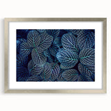 Textured art print of abstract leaves in muted green and brown shades, framed in silver, ideal for bedroom decor.