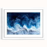 Abstract art print featuring close-up water patterns in blue and white tones, framed in white.