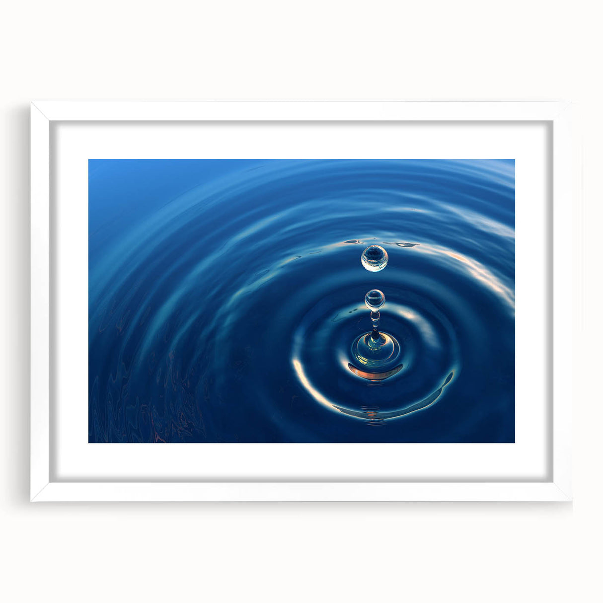 Abstract art print featuring close-up water patterns in blue and white tones, framed with a white mat.