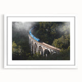 Abstract art print of a stylized train in muted gray and blue tones on a white-framed canvas.
